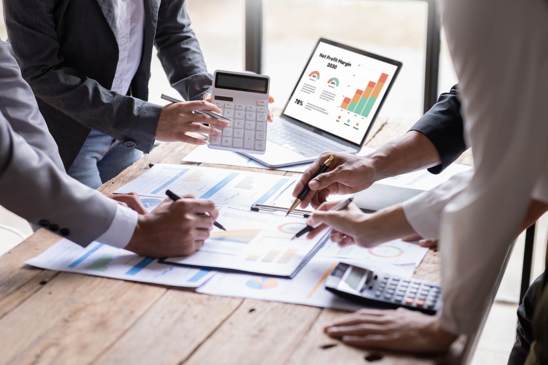 Group of confident business people point to graphs and charts to analyze market data, balance sheet, account, net profit to plan new sales strategies to increase production capacity.